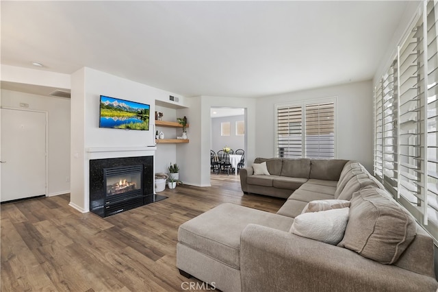 living room featuring a wealth of natural light, a fireplace with flush hearth, visible vents, and wood finished floors