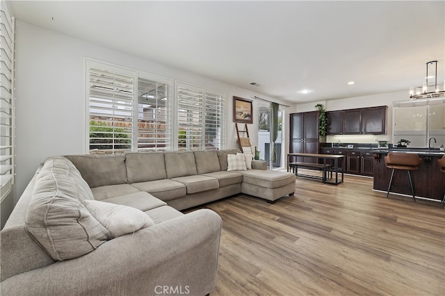 living room with recessed lighting, visible vents, and light wood finished floors