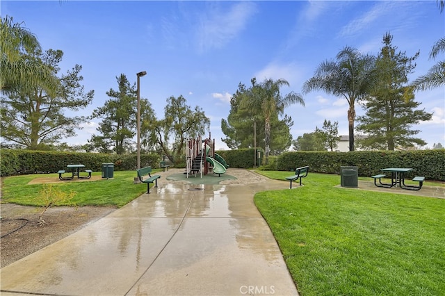 view of home's community with playground community, a yard, and fence