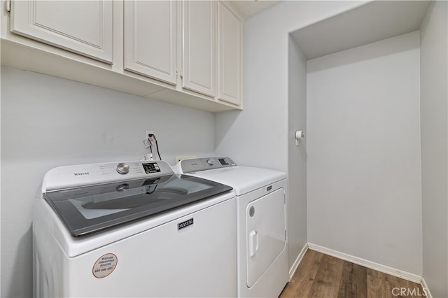 laundry area featuring dark wood finished floors, washing machine and dryer, cabinet space, and baseboards