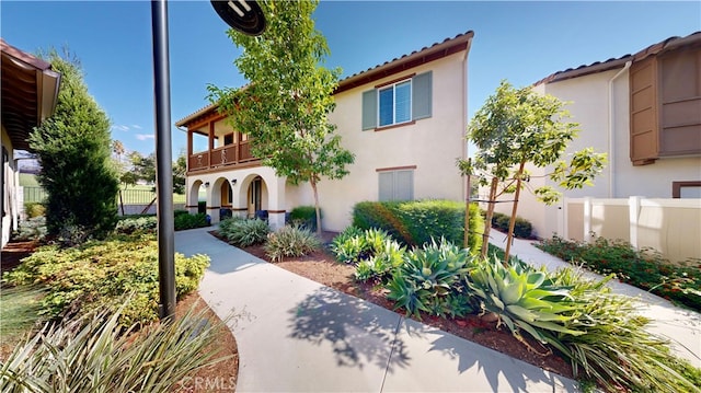 mediterranean / spanish-style home featuring stucco siding, a balcony, and fence