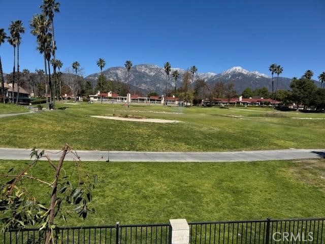 view of property's community featuring a mountain view, a yard, and fence