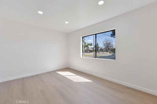 spare room with light wood finished floors, recessed lighting, and baseboards