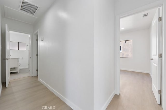 hallway featuring light wood-style flooring, visible vents, and baseboards