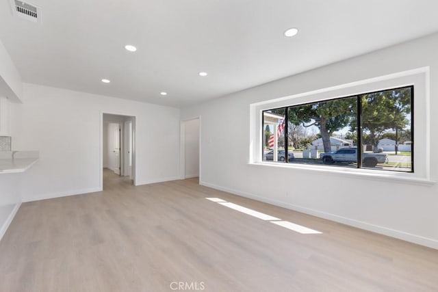 empty room featuring light wood-style floors, baseboards, visible vents, and recessed lighting