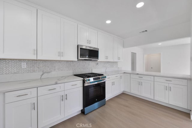 kitchen with light wood-style flooring, visible vents, white cabinets, appliances with stainless steel finishes, and light stone countertops