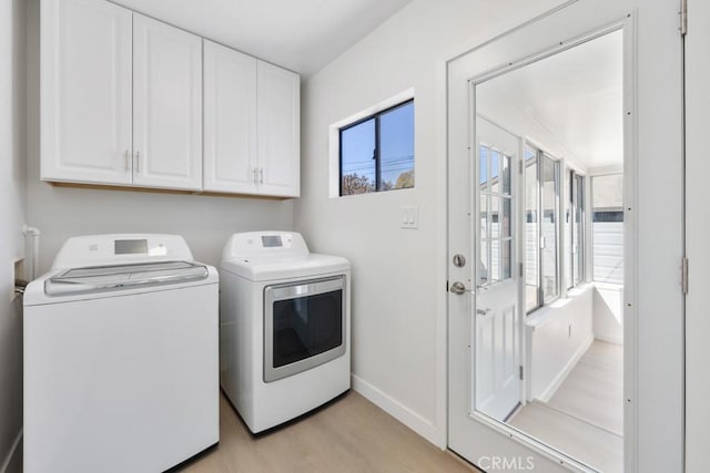 laundry area featuring light wood-style floors, cabinet space, washer and clothes dryer, and baseboards