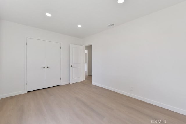 unfurnished bedroom featuring recessed lighting, a closet, visible vents, wood finished floors, and baseboards