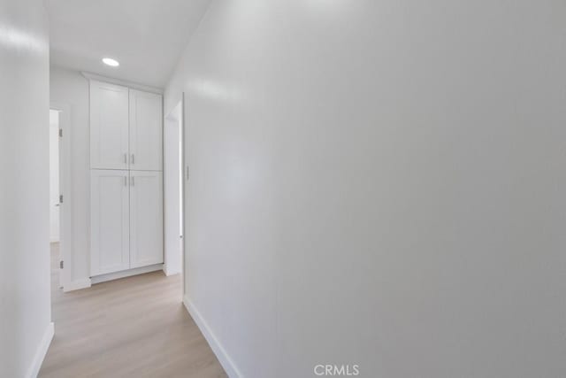 hallway featuring light wood finished floors, recessed lighting, and baseboards