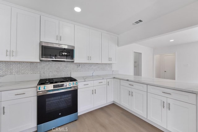 kitchen with visible vents, white cabinets, appliances with stainless steel finishes, light wood-style floors, and backsplash