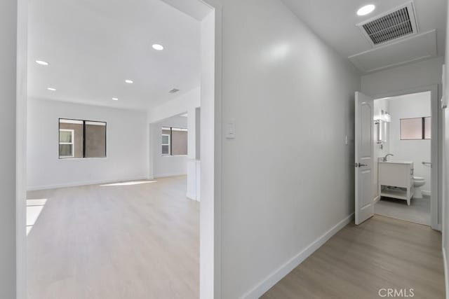 corridor featuring light wood-style flooring, recessed lighting, visible vents, and baseboards