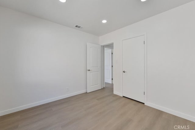 unfurnished room featuring recessed lighting, visible vents, light wood-style flooring, and baseboards