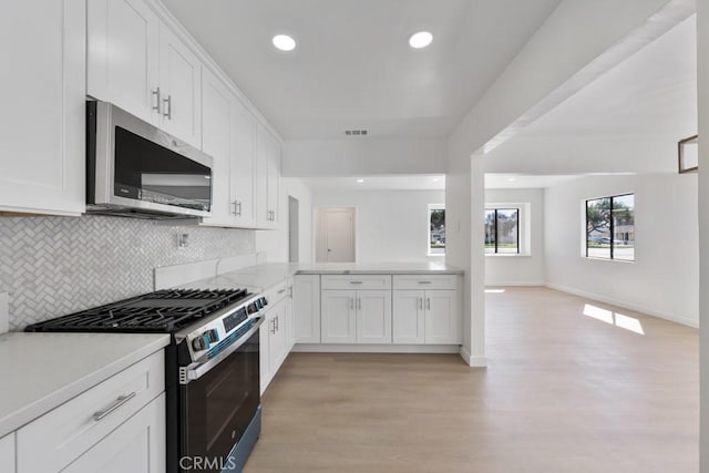 kitchen with open floor plan, light countertops, backsplash, stainless steel microwave, and gas stove