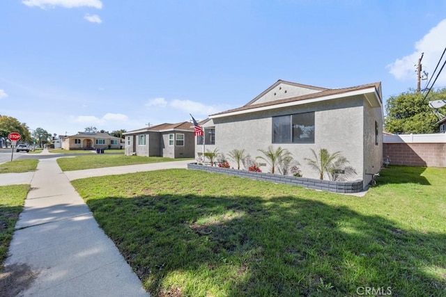 view of front facade featuring a front lawn, fence, and stucco siding