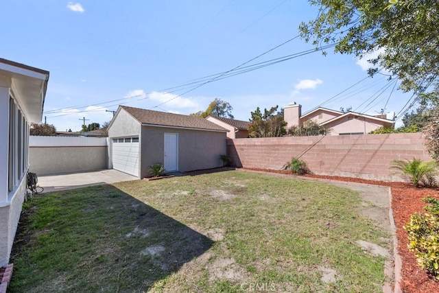 view of yard featuring a garage, a fenced backyard, and an outbuilding