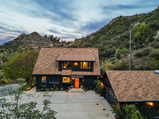 view of front of house featuring roof with shingles, a chimney, and a mountain view