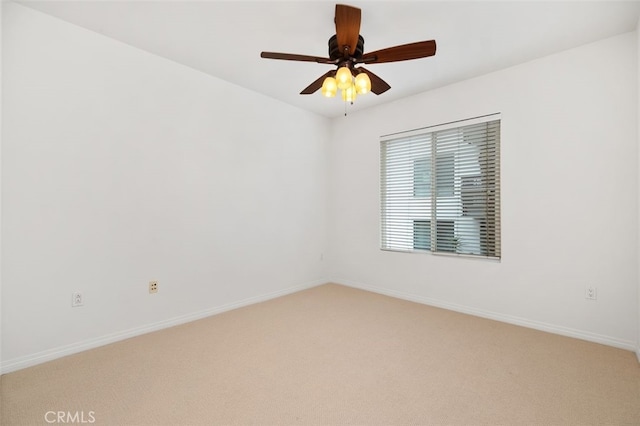 unfurnished room featuring light colored carpet, a ceiling fan, and baseboards