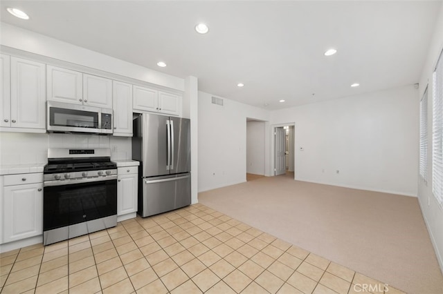 kitchen with recessed lighting, light colored carpet, appliances with stainless steel finishes, and white cabinets