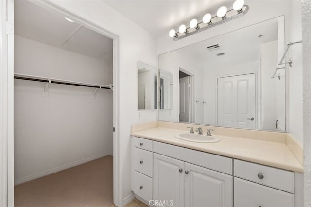 bathroom with visible vents, baseboards, a spacious closet, and vanity