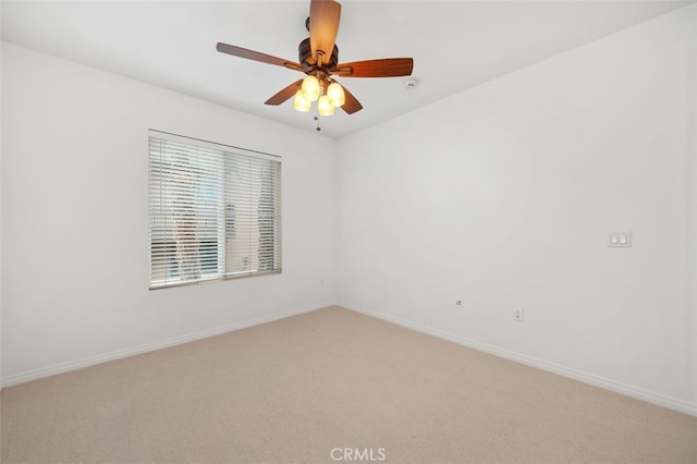 spare room with light colored carpet, baseboards, and ceiling fan