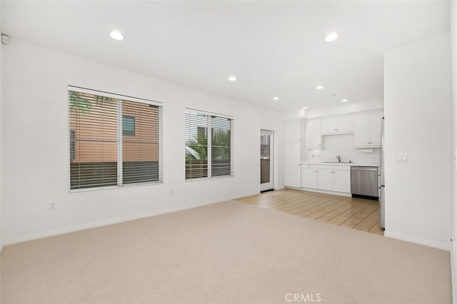 unfurnished living room featuring recessed lighting, light colored carpet, baseboards, and a sink