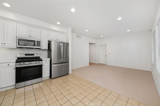 kitchen featuring stainless steel appliances, light colored carpet, visible vents, and white cabinetry