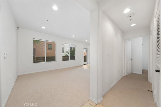 hallway featuring recessed lighting, baseboards, and light carpet