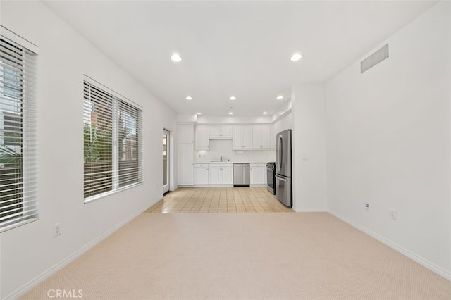 unfurnished living room with visible vents, baseboards, light colored carpet, recessed lighting, and a sink