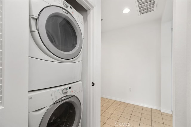 laundry area featuring visible vents, recessed lighting, light tile patterned floors, stacked washer / drying machine, and baseboards