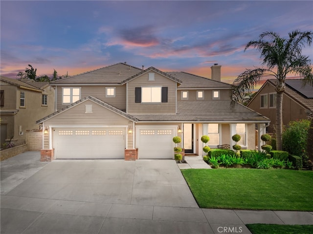 traditional-style home with a garage, brick siding, a tiled roof, driveway, and a front yard