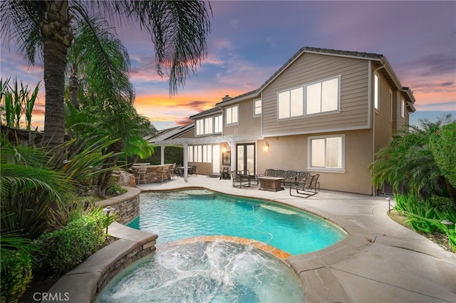 back of house featuring a fire pit, an outdoor pool, a patio, an in ground hot tub, and stucco siding