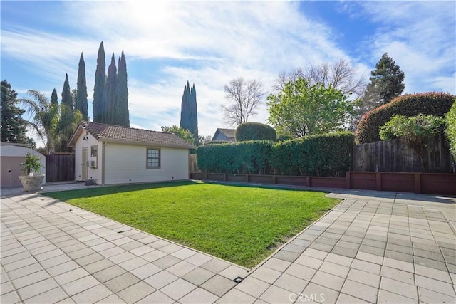 view of yard featuring an outbuilding, fence, and a patio area