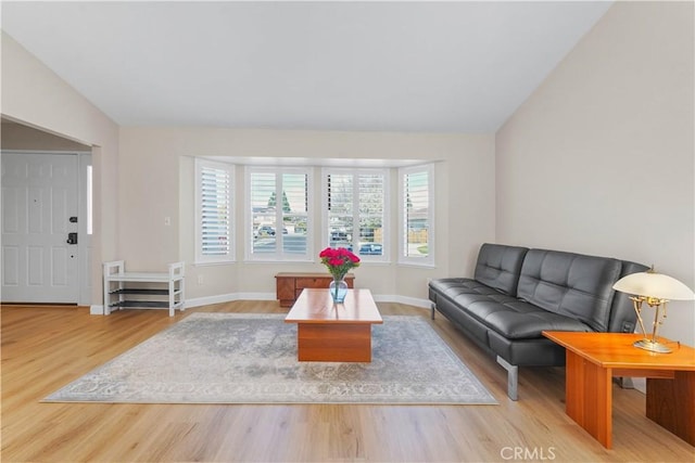 living area with vaulted ceiling, wood finished floors, and baseboards