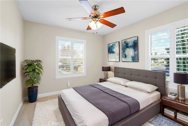 bedroom featuring a ceiling fan, carpet flooring, baseboards, and multiple windows
