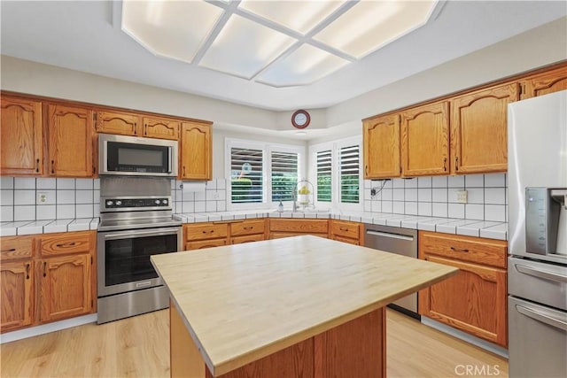 kitchen with tasteful backsplash, light wood finished floors, and appliances with stainless steel finishes