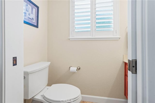 half bathroom with vanity, baseboards, and toilet