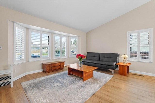 living area featuring visible vents, wood finished floors, baseboards, and vaulted ceiling