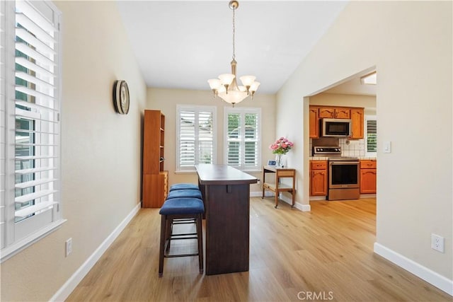 dining room with light wood finished floors, baseboards, an inviting chandelier, and vaulted ceiling