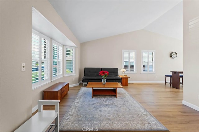 living room with baseboards, light wood-type flooring, and lofted ceiling