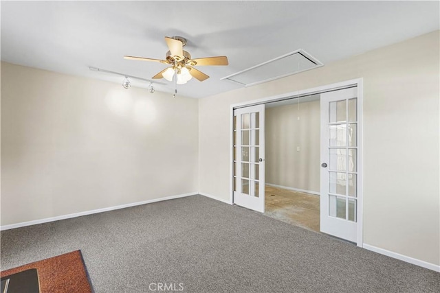 carpeted empty room with baseboards, track lighting, french doors, attic access, and a ceiling fan