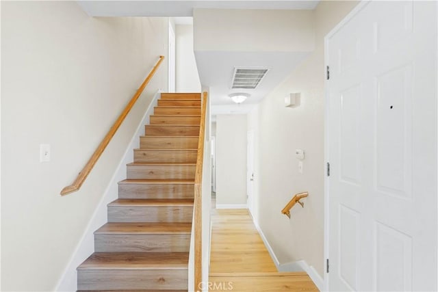 staircase with wood finished floors, visible vents, and baseboards