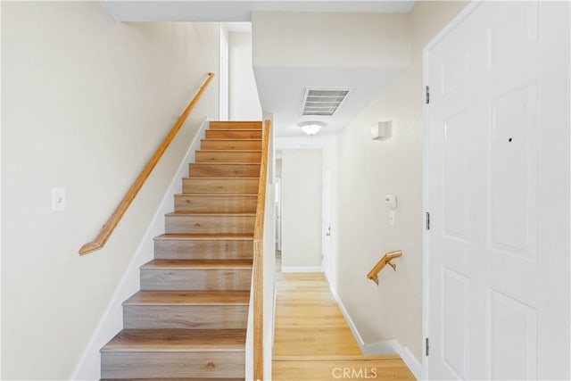 staircase featuring wood finished floors, baseboards, and visible vents