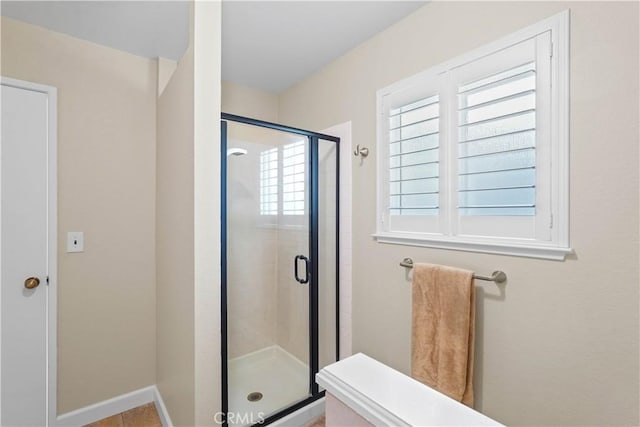 full bath with a shower stall and baseboards