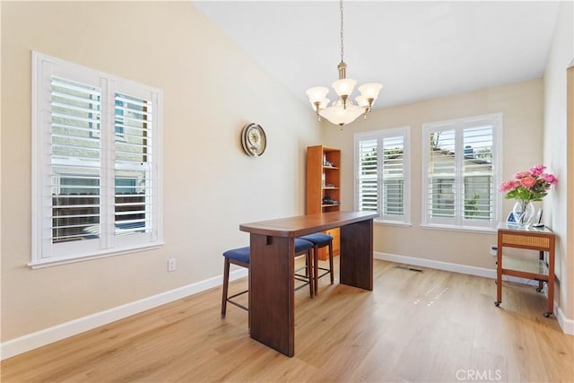 office space featuring a chandelier, light wood-style flooring, baseboards, and vaulted ceiling