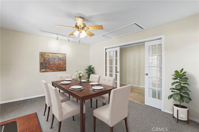 carpeted dining area with baseboards, rail lighting, attic access, and ceiling fan