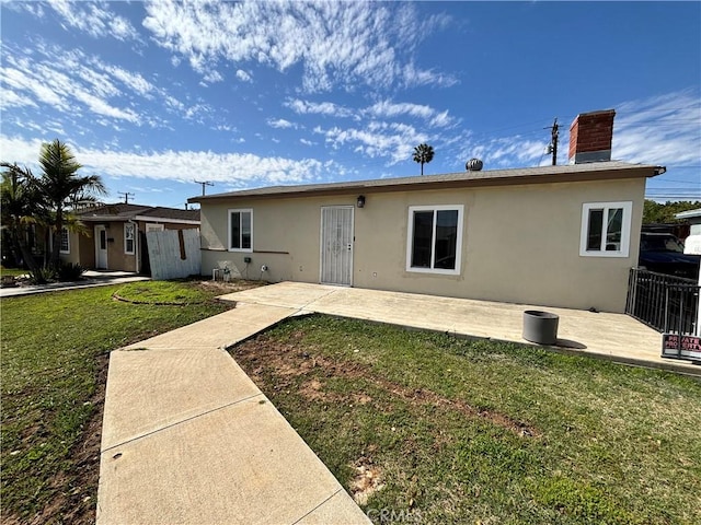 back of property featuring a patio, a lawn, and stucco siding