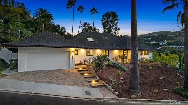 view of front of home with a garage, decorative driveway, and stucco siding