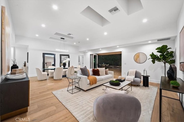 living room featuring light wood-style floors, visible vents, and recessed lighting