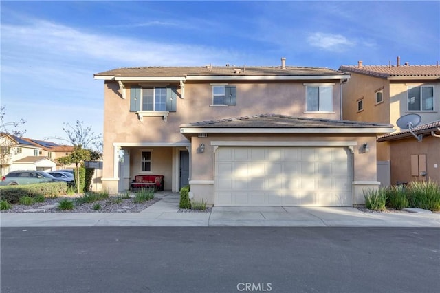 traditional-style home featuring driveway, an attached garage, and stucco siding