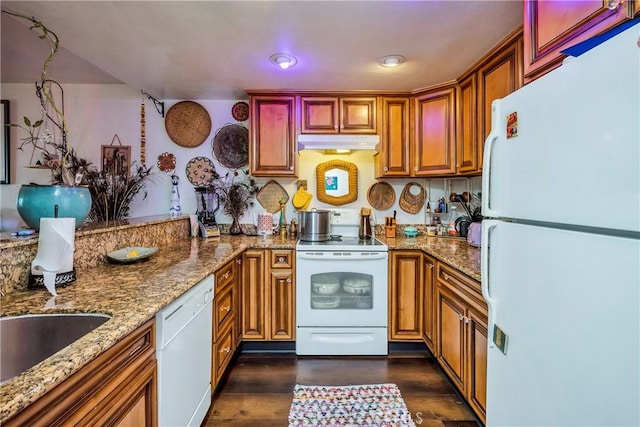 kitchen with white appliances, stone countertops, under cabinet range hood, and dark wood-style flooring